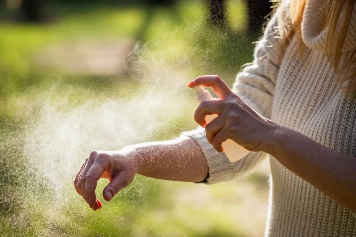 Woman applying personal repellent outdoors at golden hour